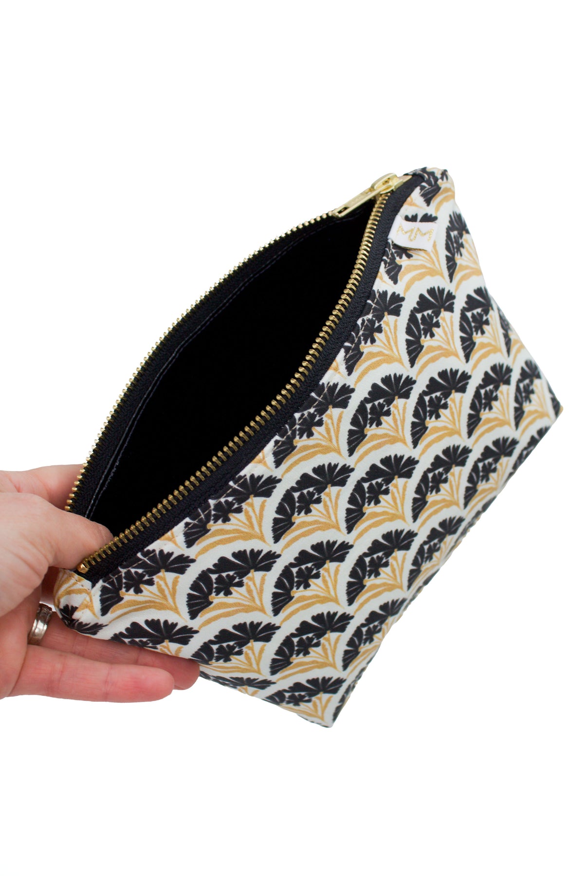 Hand holding the Art Deco Scallop Classic Mini Maxx bag to show its size, structured shape and black and gold floral design.